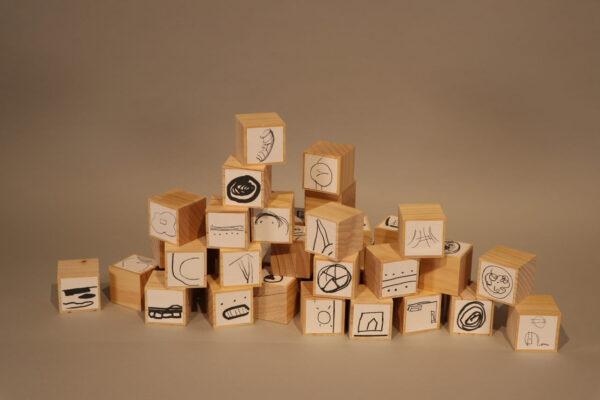 Image of several wooden block with black and white symbols on the front of each block stacked in a loose triangle.